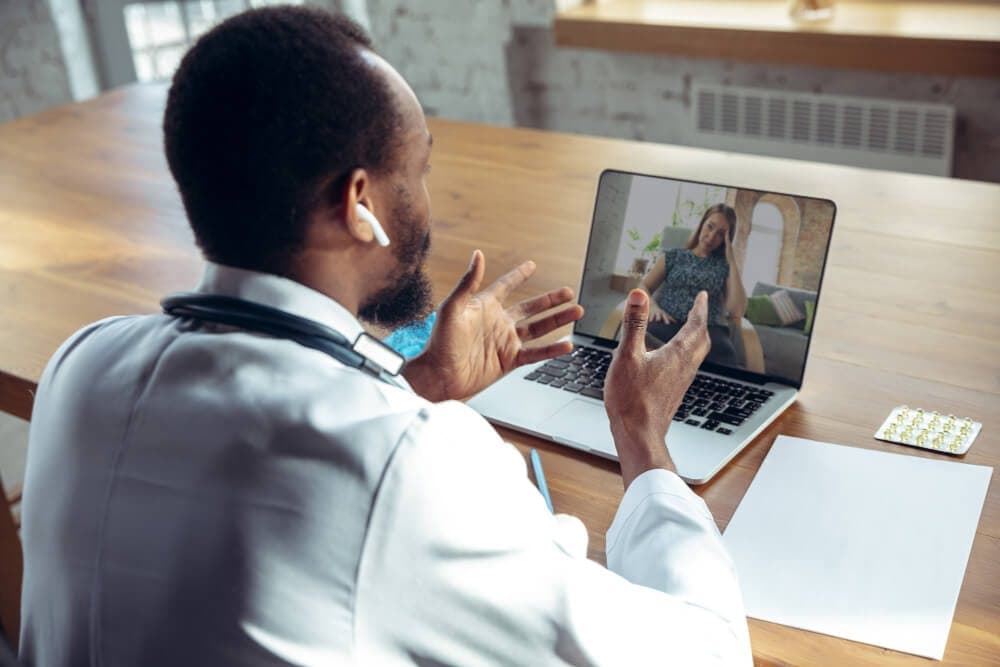 Médico atendendo por telemedicina com um computador